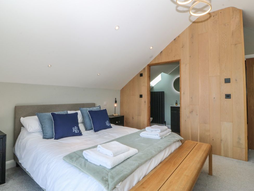 A bedroom with a bed, towels on the bed, and a door at The Hideaway in Mynytho near Abersoch