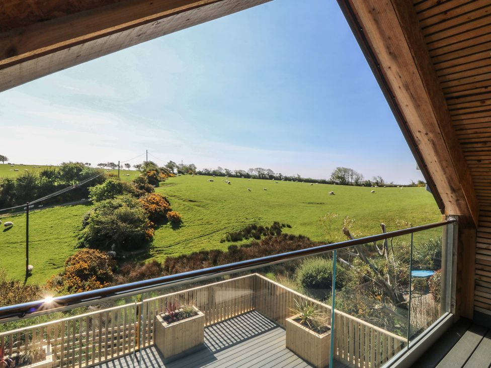 A view from a balcony overlooking fields and cattle at The Hideaway Mynytho near Abersoch