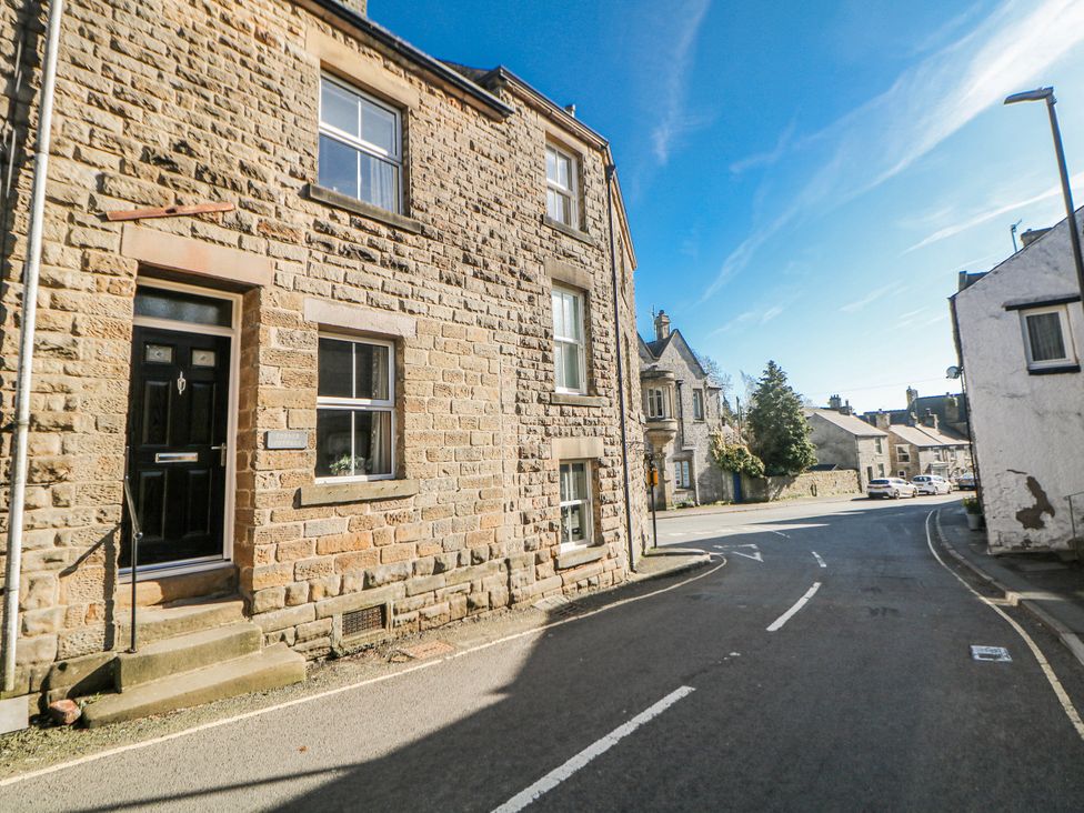 A street view of a stone building with windows and a front door at Corner Cottage in Tideswell