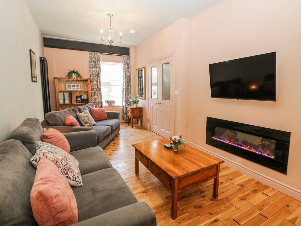 A living room with a sofa, coffee table and television at Corner Cottage in Tideswell