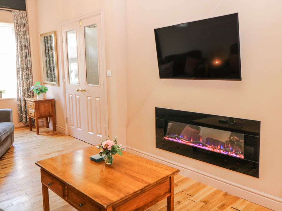 A living room with a television and electric fireplace at Corner Cottage in Tideswell
