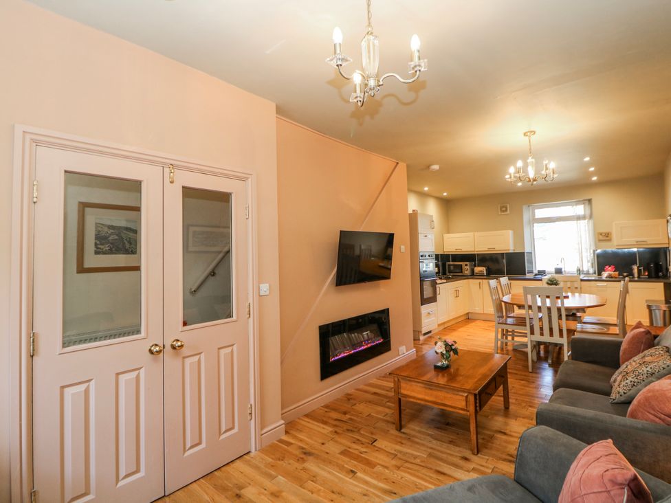 A living room with a fireplace and dining area at Corner Cottage in Tideswell
