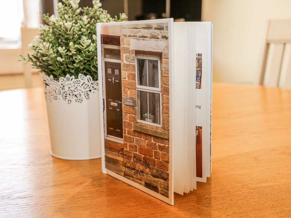 A book on a table with a plant at Corner Cottage in Tideswell