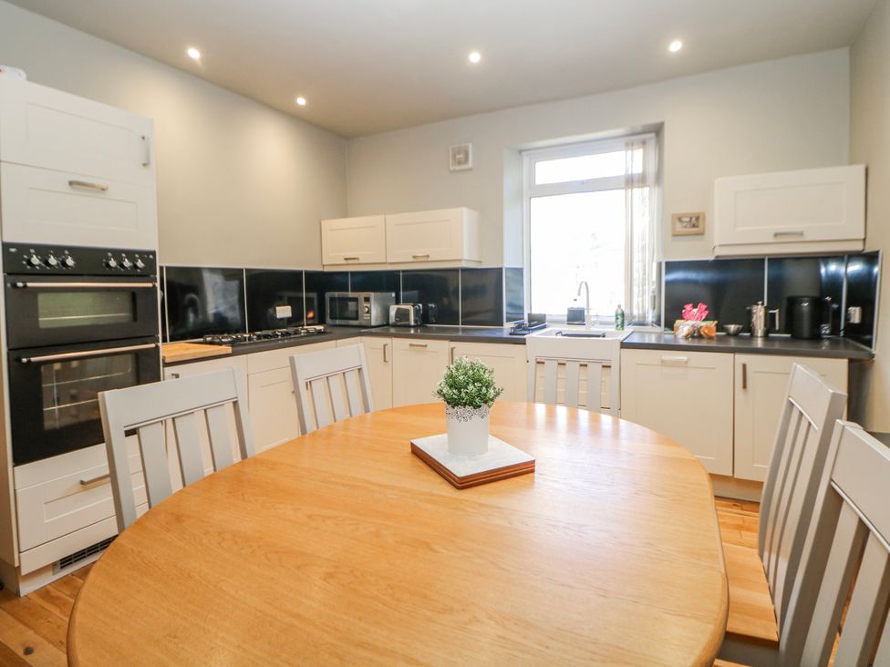 A kitchen with appliances and a dining table at Corner Cottage in Tideswell