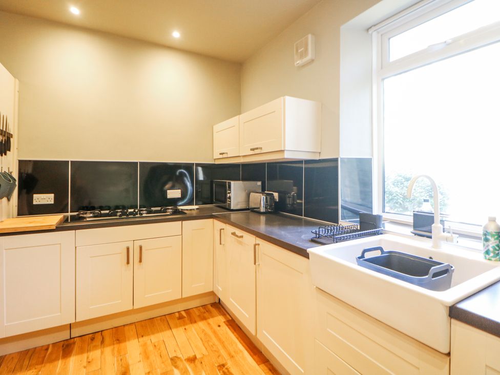 A kitchen featuring a gas stove and microwave at Corner Cottage in Tideswell