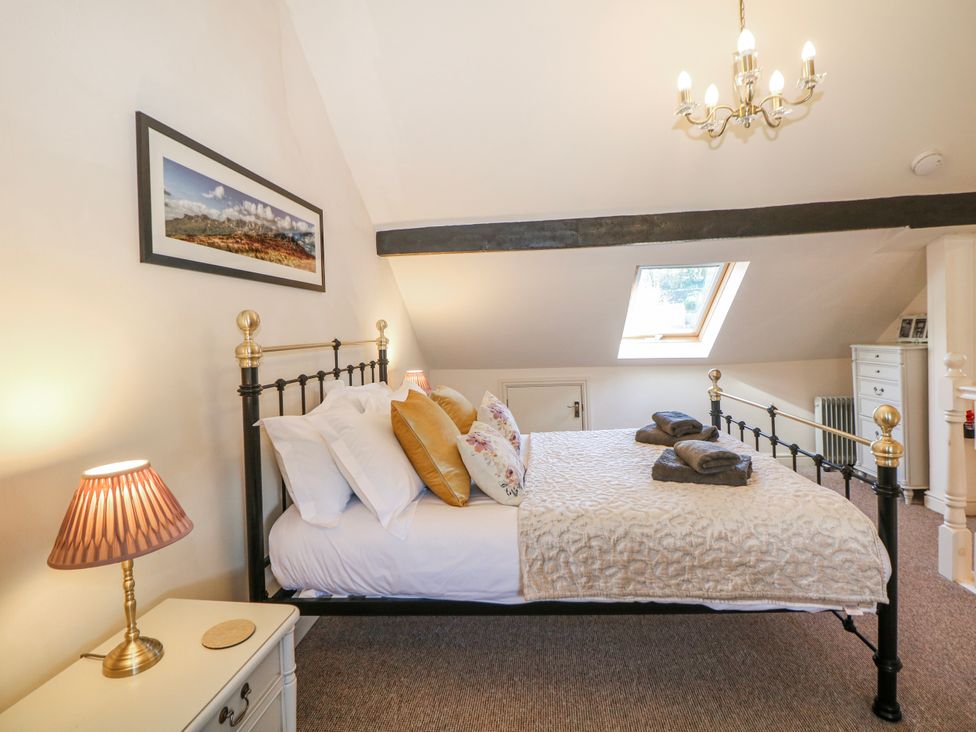 A bedroom with a bed and a lamp at Corner Cottage in Tideswell