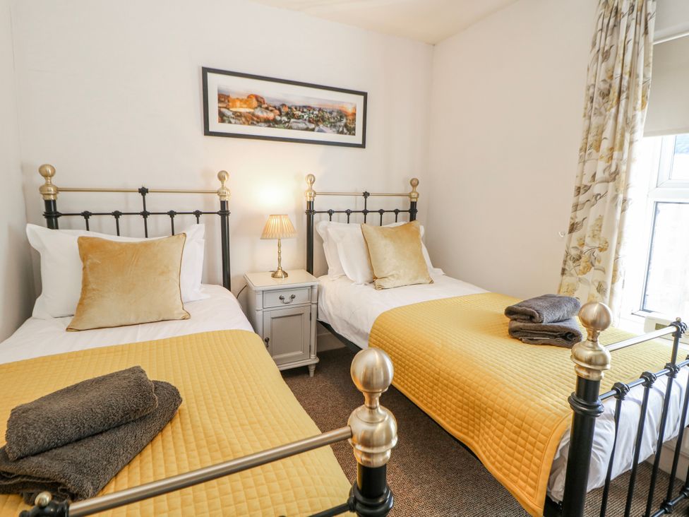 A bedroom with two beds and a bedside table at Corner Cottage in Tideswell
