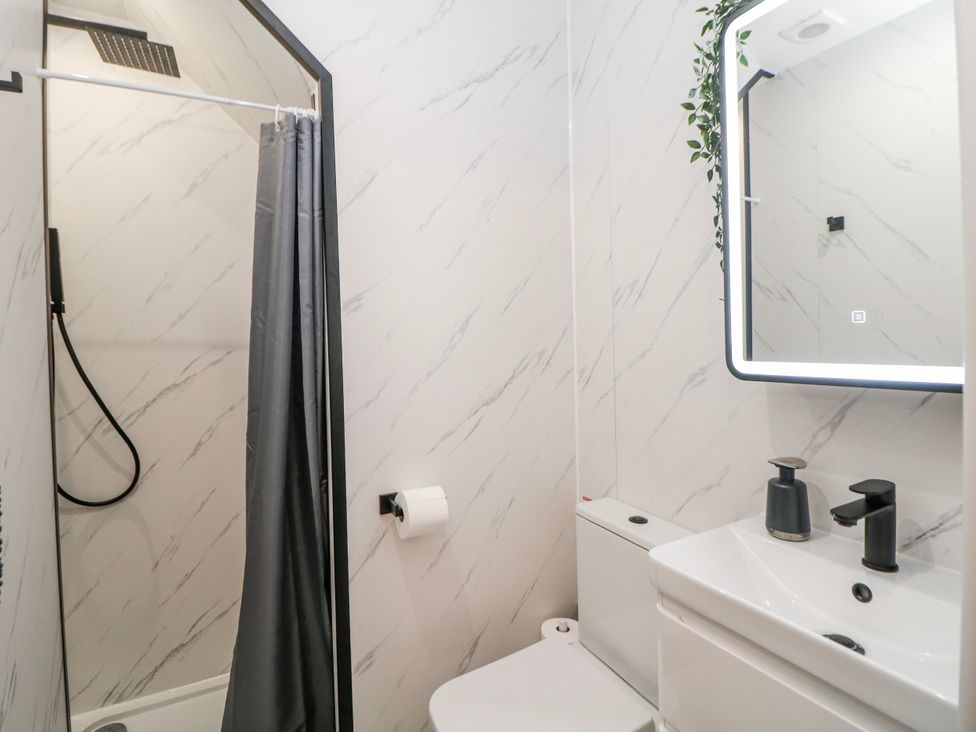 A bathroom featuring a shower, toilet, and sink at Corner Cottage in Tideswell