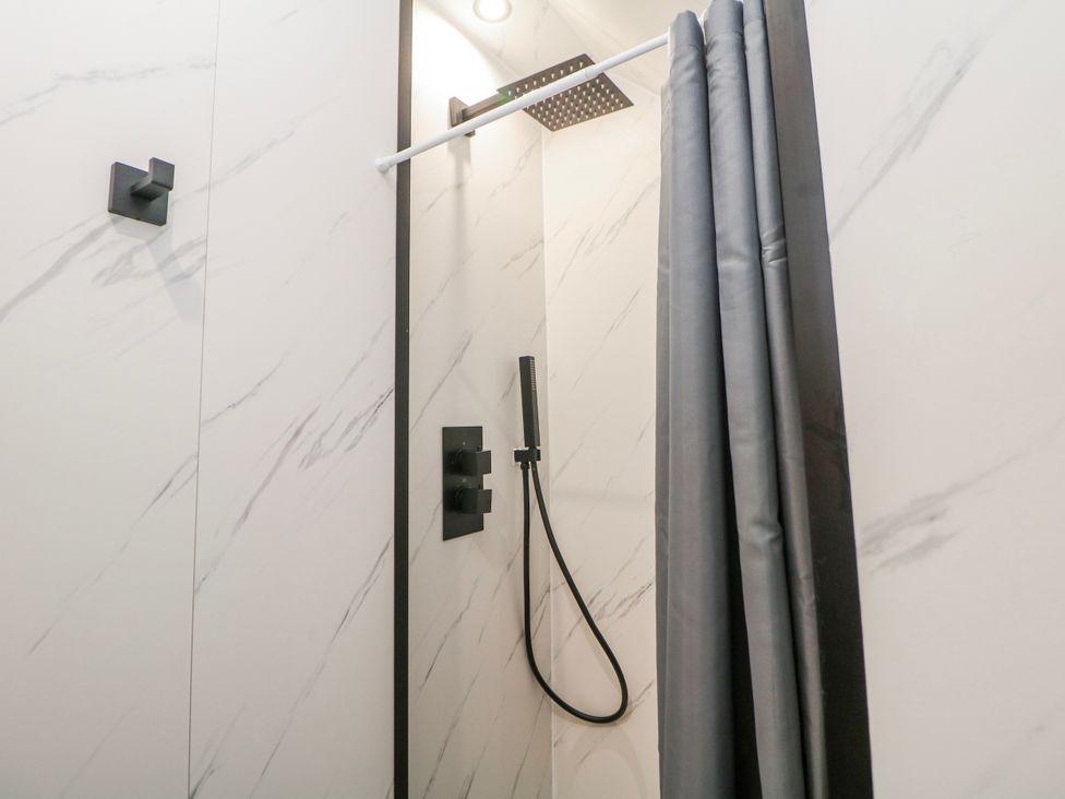 A shower with a curtain and a showerhead at Corner Cottage Tideswell