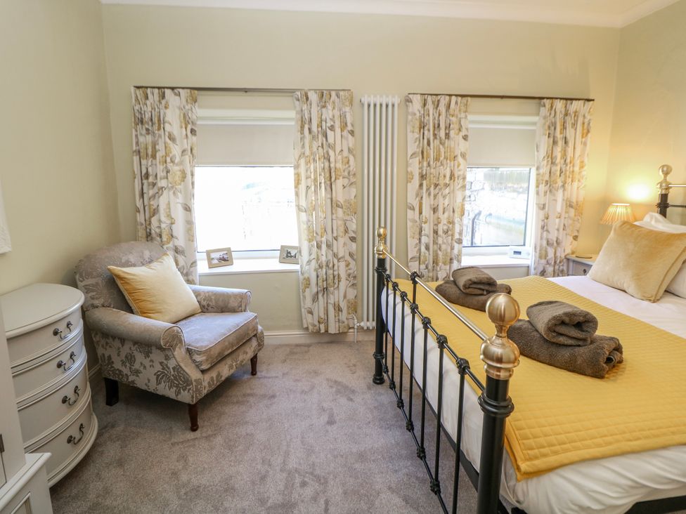 A bedroom with a bed and armchair at Corner Cottage in Tideswell
