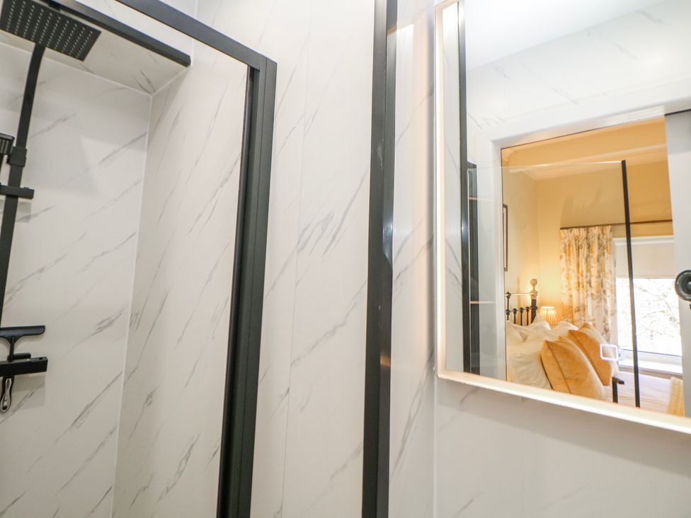 A bathroom with a shower and mirror at Corner Cottage in Tideswell