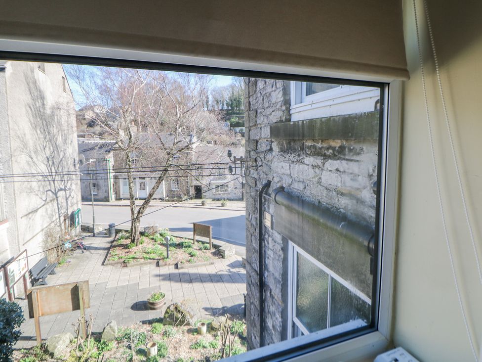 A view from a window showing a street with trees and buildings at Corner Cottage in Tideswell