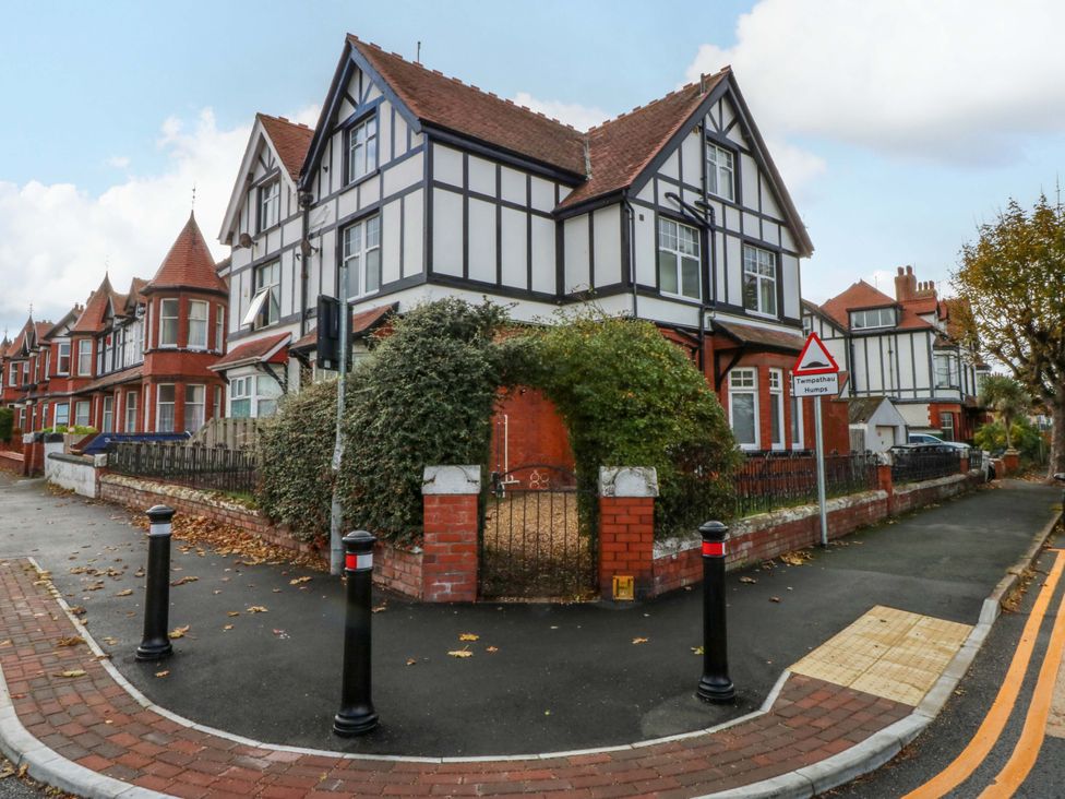 A house with a fence and street sign at Queens Park in Llandudno