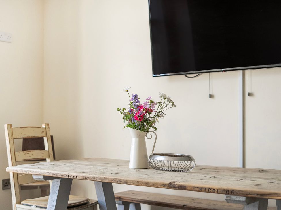 A dining room with a table and flowers at Hay Store in Corwen