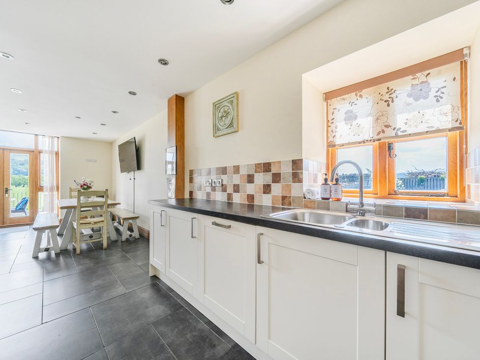 A kitchen with a sink, dining table and chairs at Hay Store in Corwen