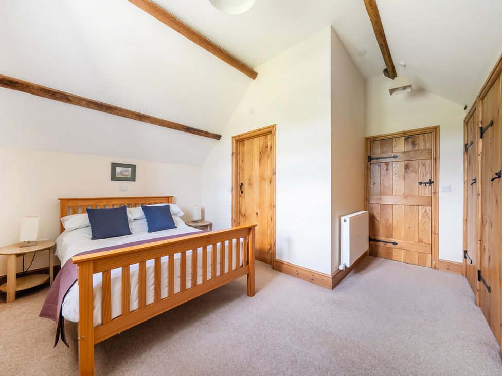A bedroom with a bed and wooden doors at Hay Store in Corwen