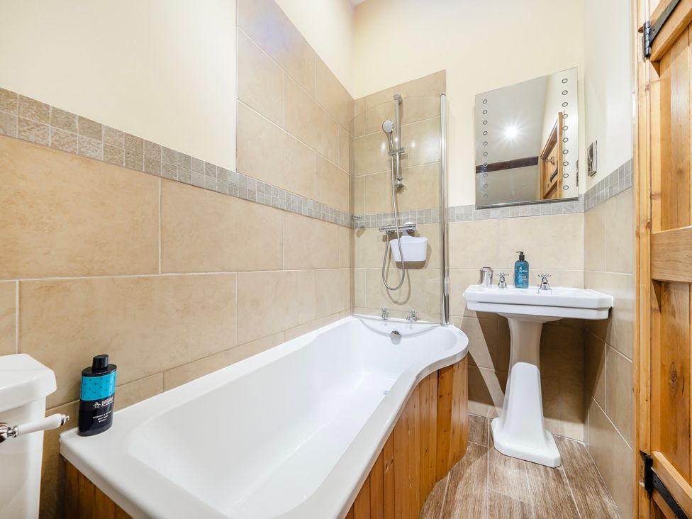 A bathroom with a bathtub, shower, and sink at Hay Store in Corwen