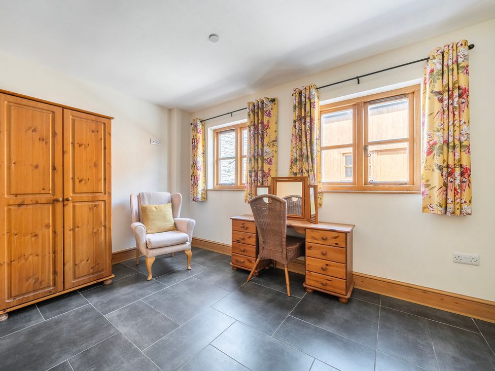 A bedroom with a wardrobe, desk and armchair at Hay Store in Corwen