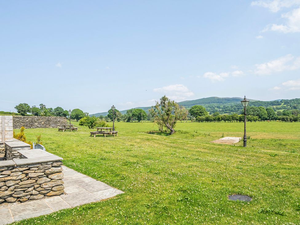 An outdoor area with picnic tables and a stone wall at Hay Store in Corwen