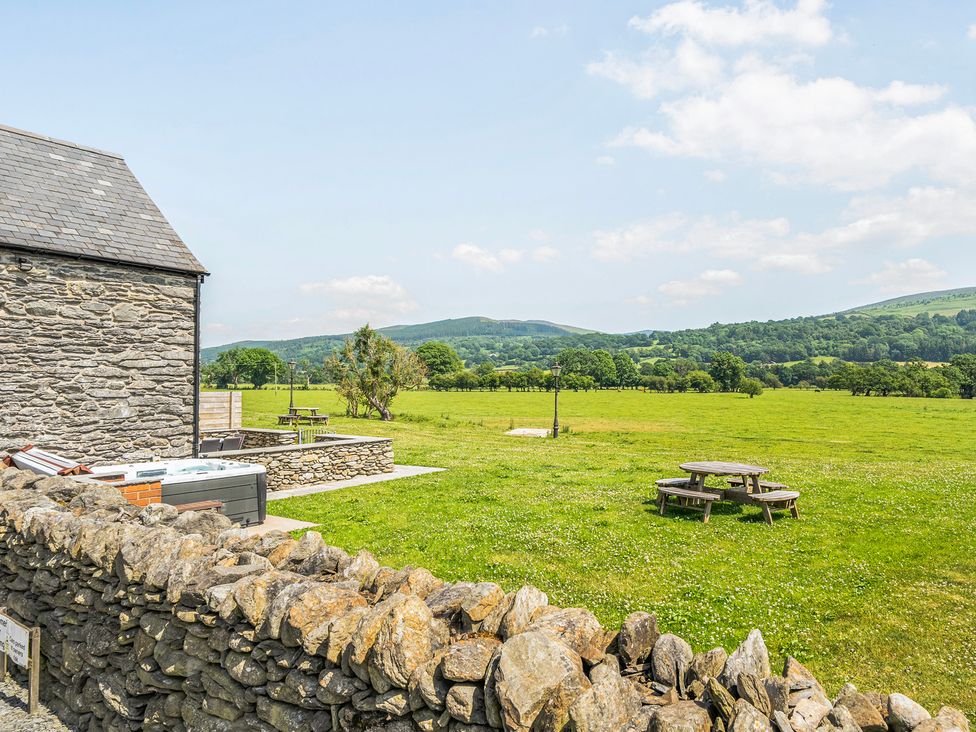 An outdoor area with a stone building and picnic table at Hay Store in Corwen