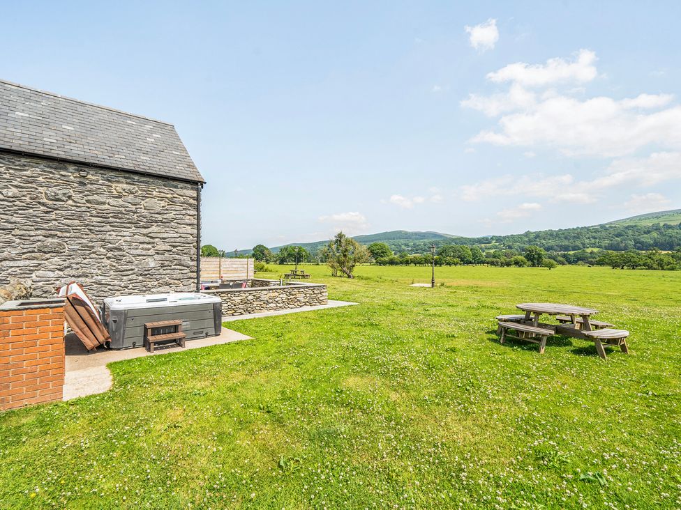 An outdoor area with a stone building and picnic table at Hay Store in Corwen