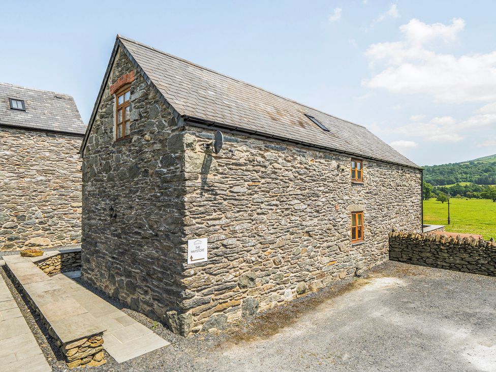 A stone building with windows and a sign at Hay Store in Corwen