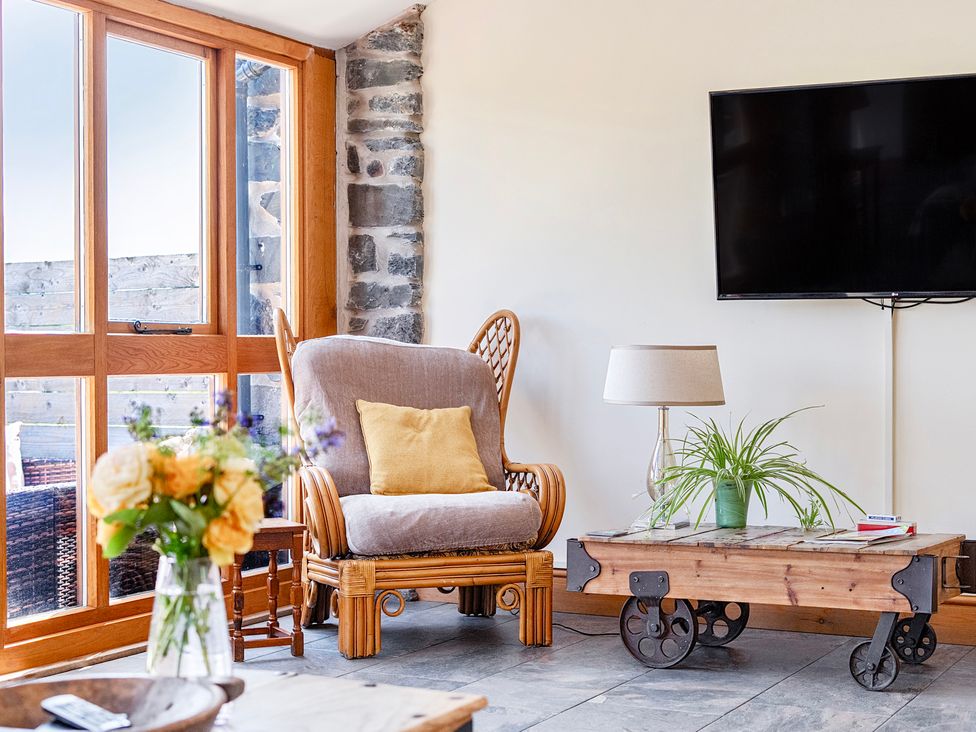 A living room with an armchair and a coffee table at The Barn in Corwen