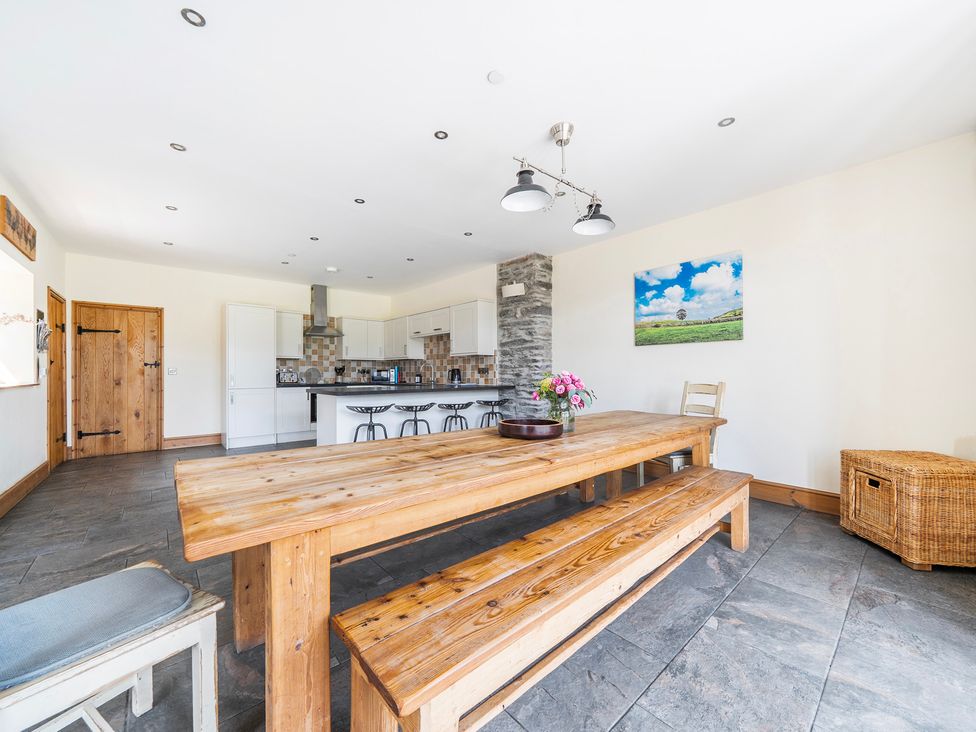 A dining room with a wooden table and kitchen area at The Barn in Corwen