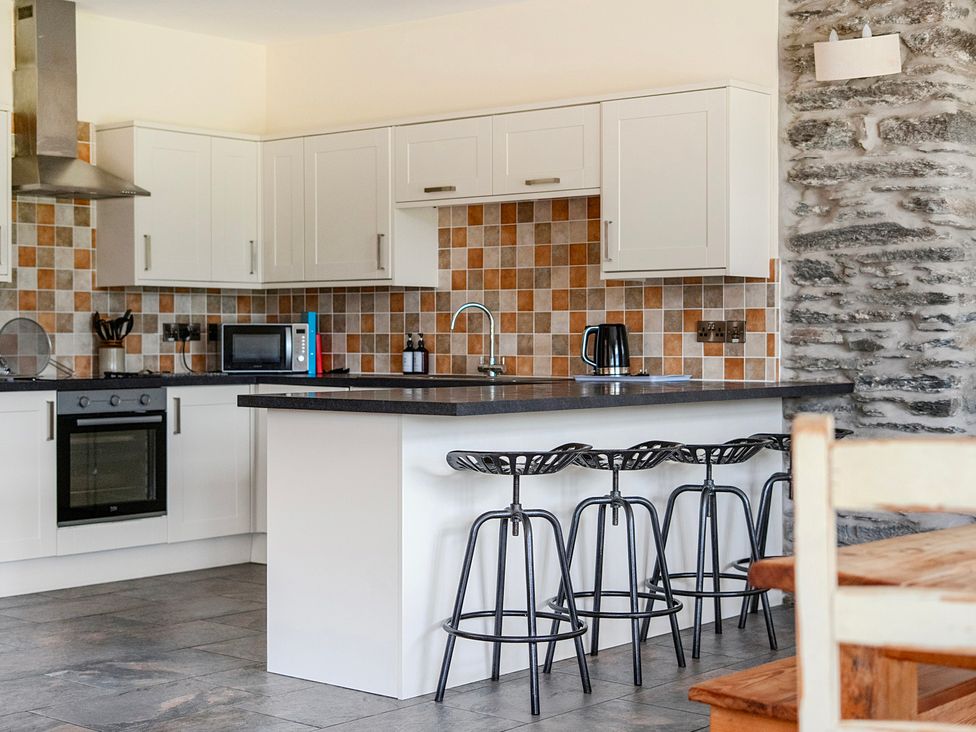 A kitchen with stools and appliances at The Barn in Corwen