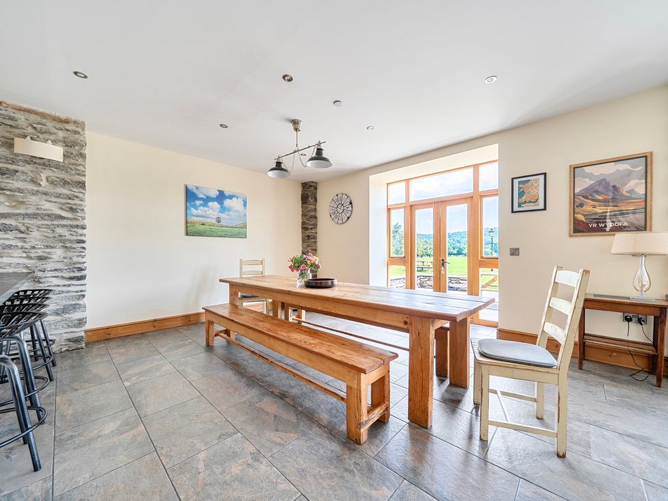 A dining room with a large table and benches at The Barn in Corwen