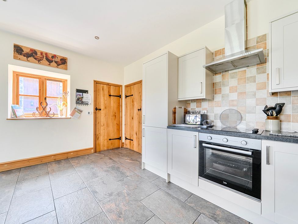 A kitchen with fitted cabinets and an oven at The Barn in Corwen