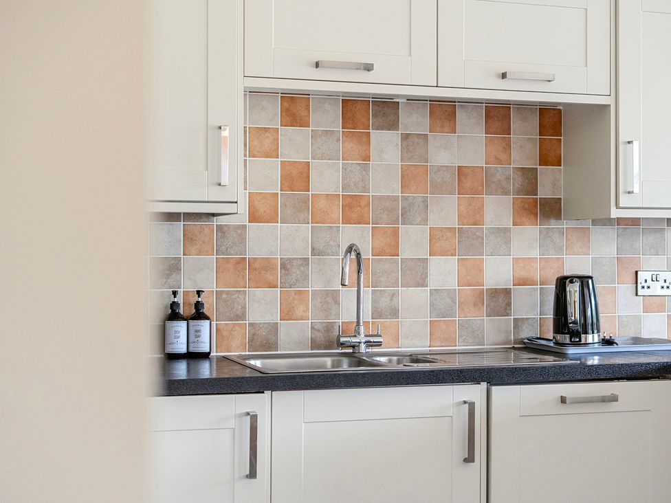 A kitchen with tiles and a sink at The Barn in Corwen