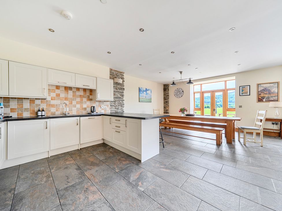 A kitchen with a dining table and chairs at The Barn in Corwen