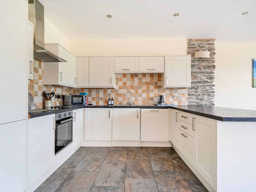A kitchen with cabinets, oven, and microwave at The Barn in Corwen