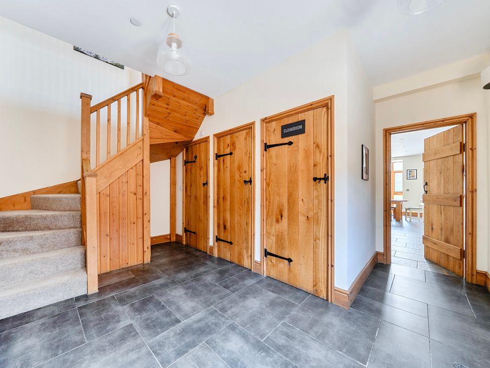 A hallway with a staircase and closet doors at The Barn in Corwen
