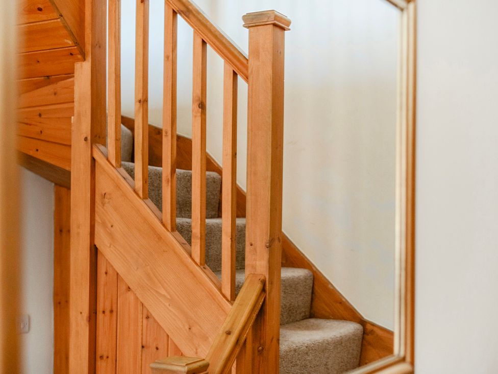 A staircase with wooden handrail and carpet at The Barn in Corwen