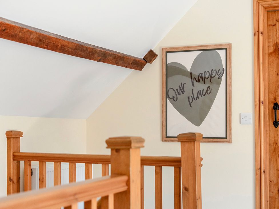A hallway with wooden railing and a framed picture at The Barn in Corwen