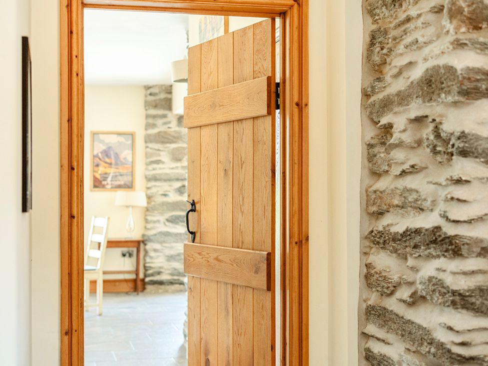 A wooden door opening to a hallway with a table and chair at The Barn in Corwen