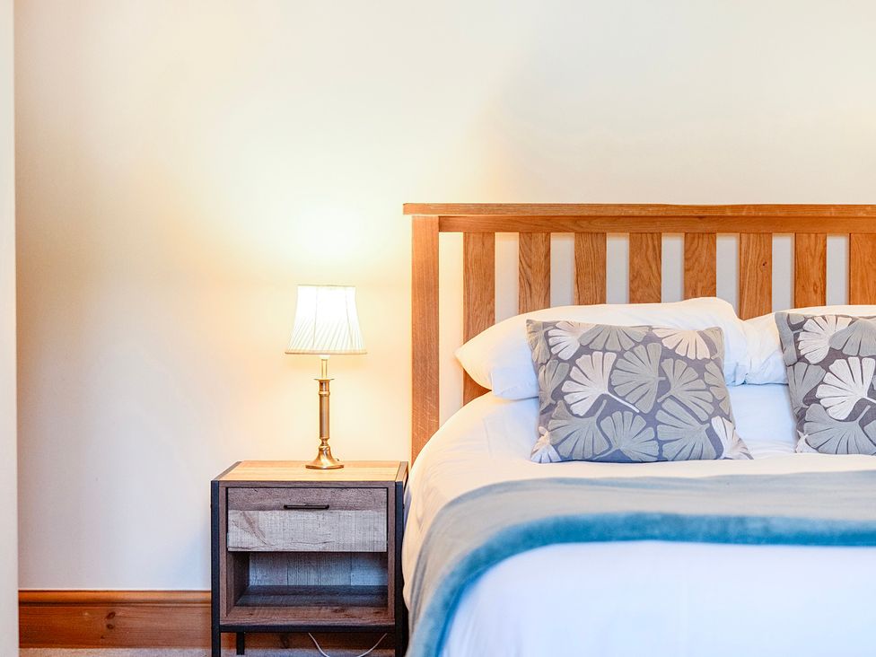 A bedroom with a bed and nightstand at The Barn in Corwen