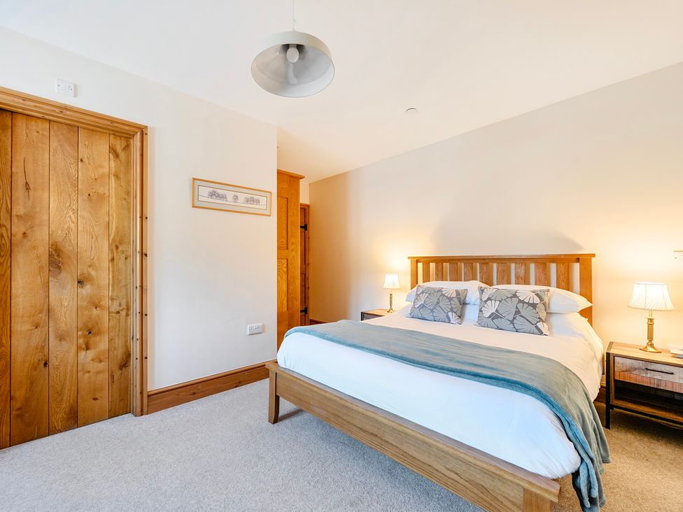 A bedroom with a bed and bedside tables at The Barn in Corwen