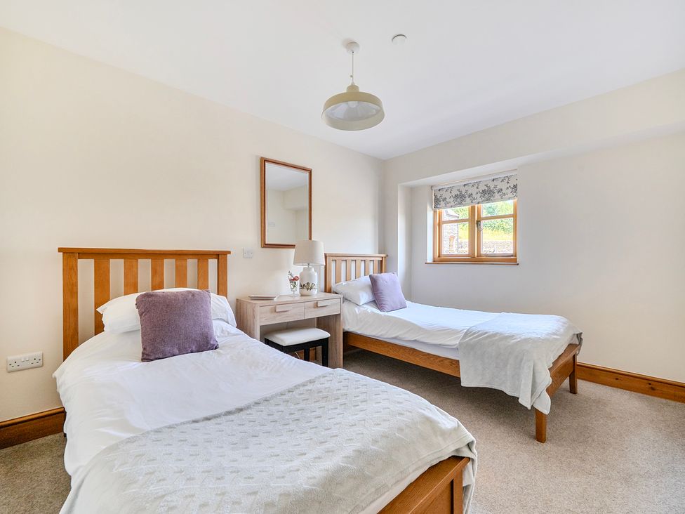 A bedroom with two beds and a bedside table at The Barn in Corwen