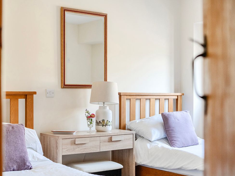 A bedroom with two beds and a lamp on a table at The Barn in Corwen