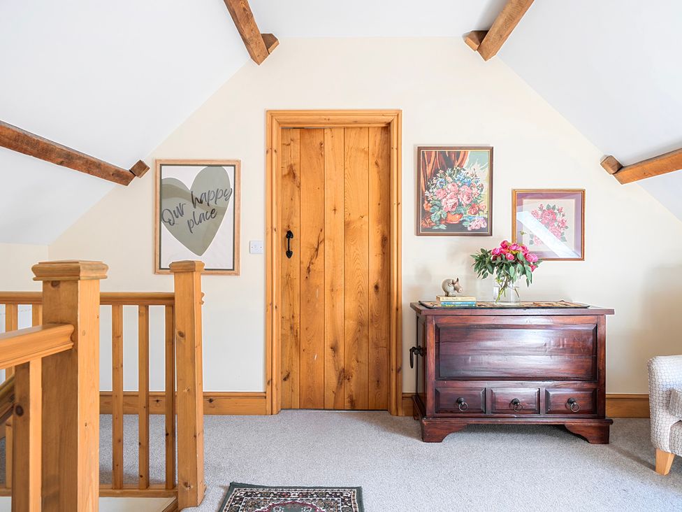 A landing area with a wooden door and artwork on the wall at The Barn in Corwen