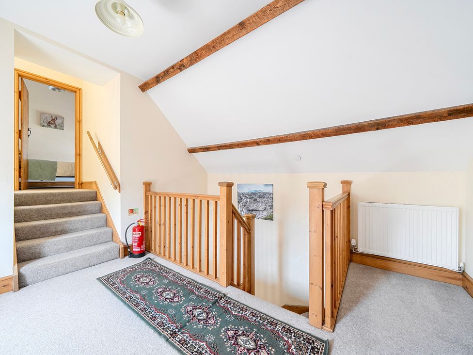 A hallway with a staircase and rug at The Barn in Corwen