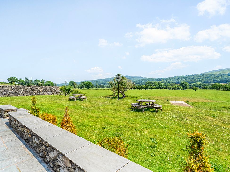 A garden with tables and benches at The Barn in Corwen