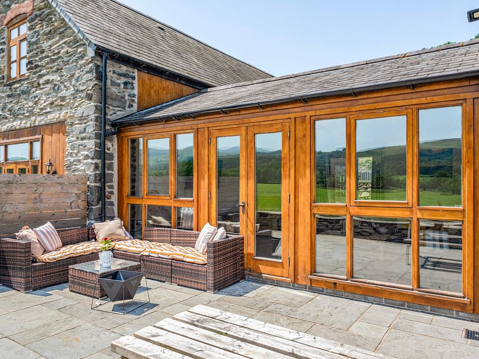 An outdoor seating area with a rattan sofa and table at The Barn in Corwen