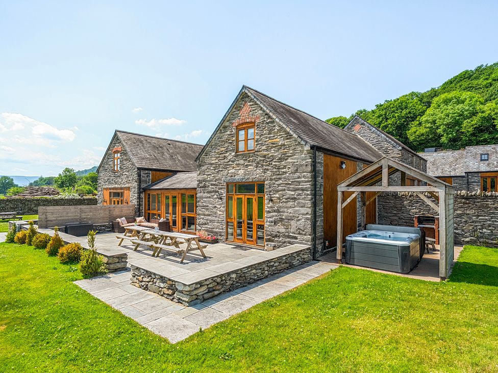 An outdoor area with a hot tub and seating at The Barn in Corwen