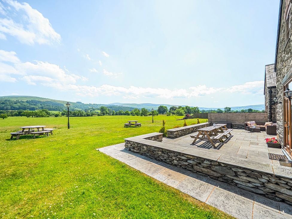 An outdoor area with picnic tables and a stone patio at The Barn in Corwen