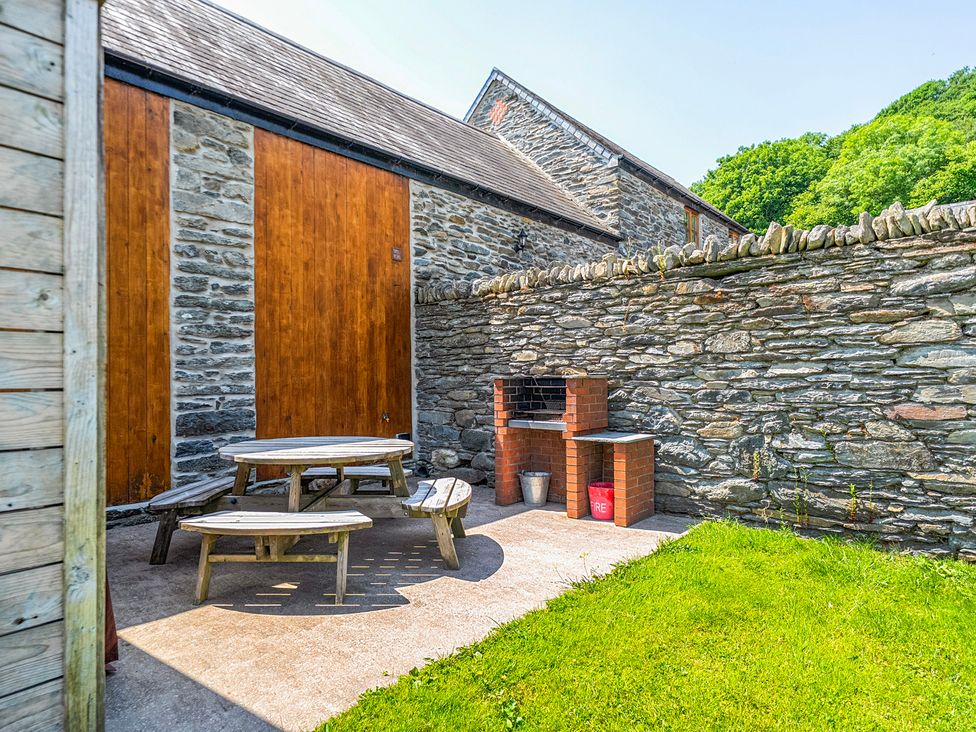 An outdoor space with a table and benches at The Barn in Corwen