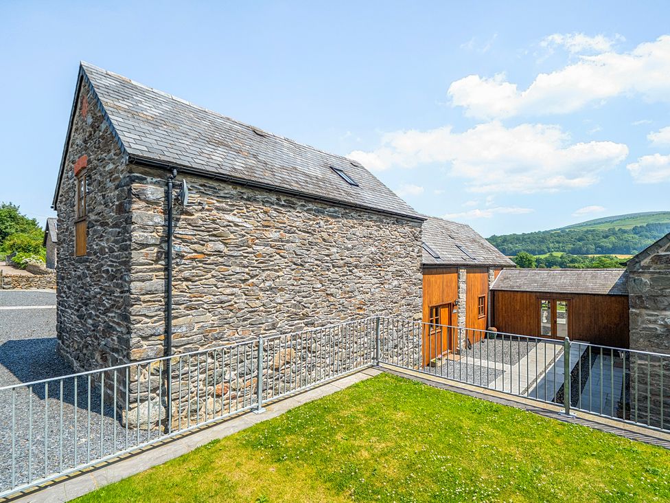 An outdoor area with stone and wooden houses at The Barn in Corwen